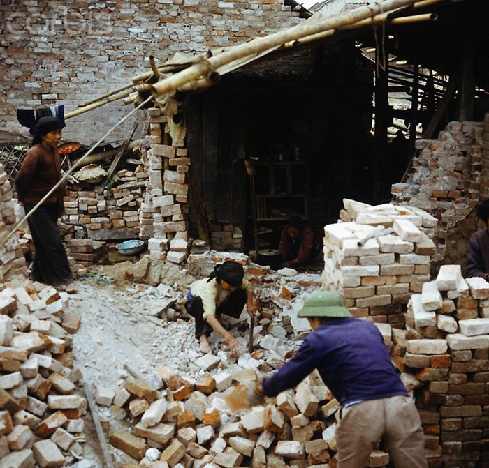Tháng 3/1973. Một gia đình đang chặt những viên gạch để dùng lại cho một căn nhà dựng tạm tại phố Khâm Thiên. Ảnh. Werner Schulze/Corbis.